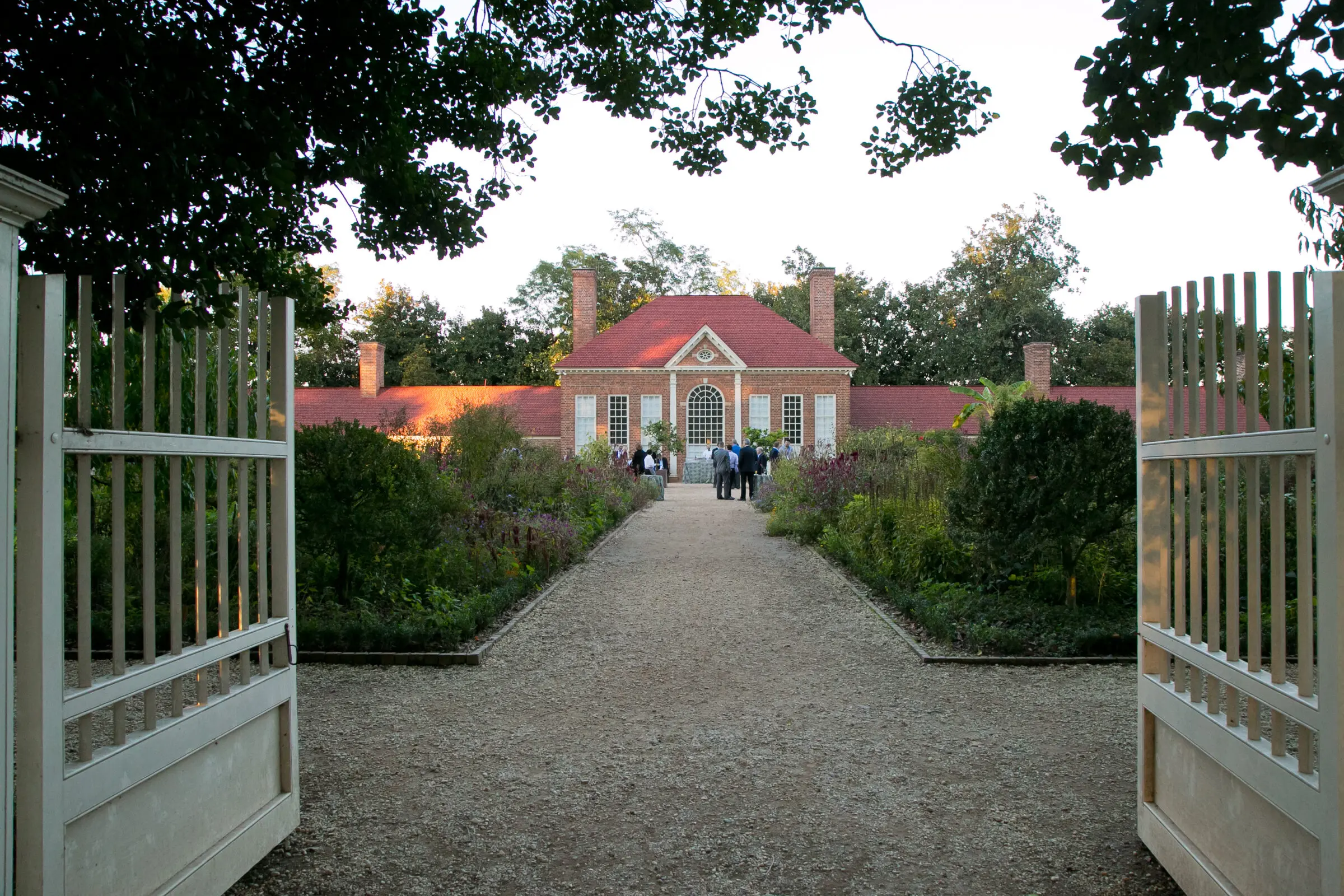The exterior of George Washington's Mount Vernon, framed by gates leading down a path to a brick building.