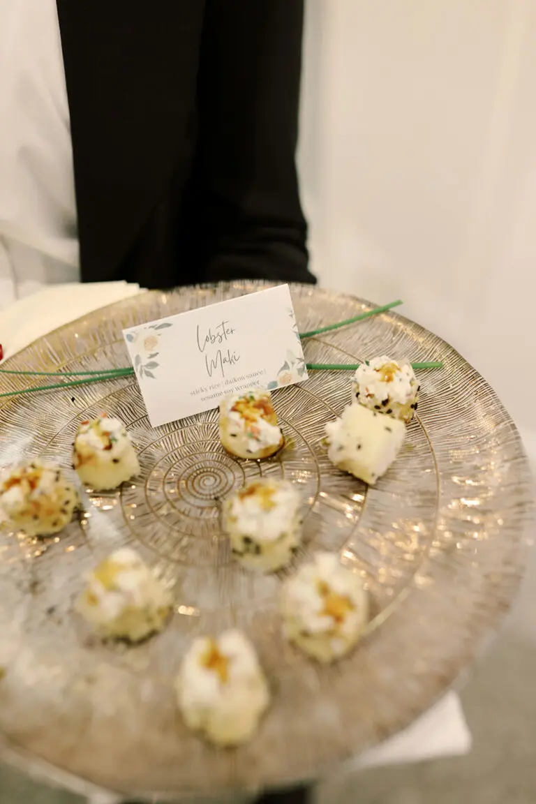 Lobster maki hors d'oeuvres on a round silver tray.