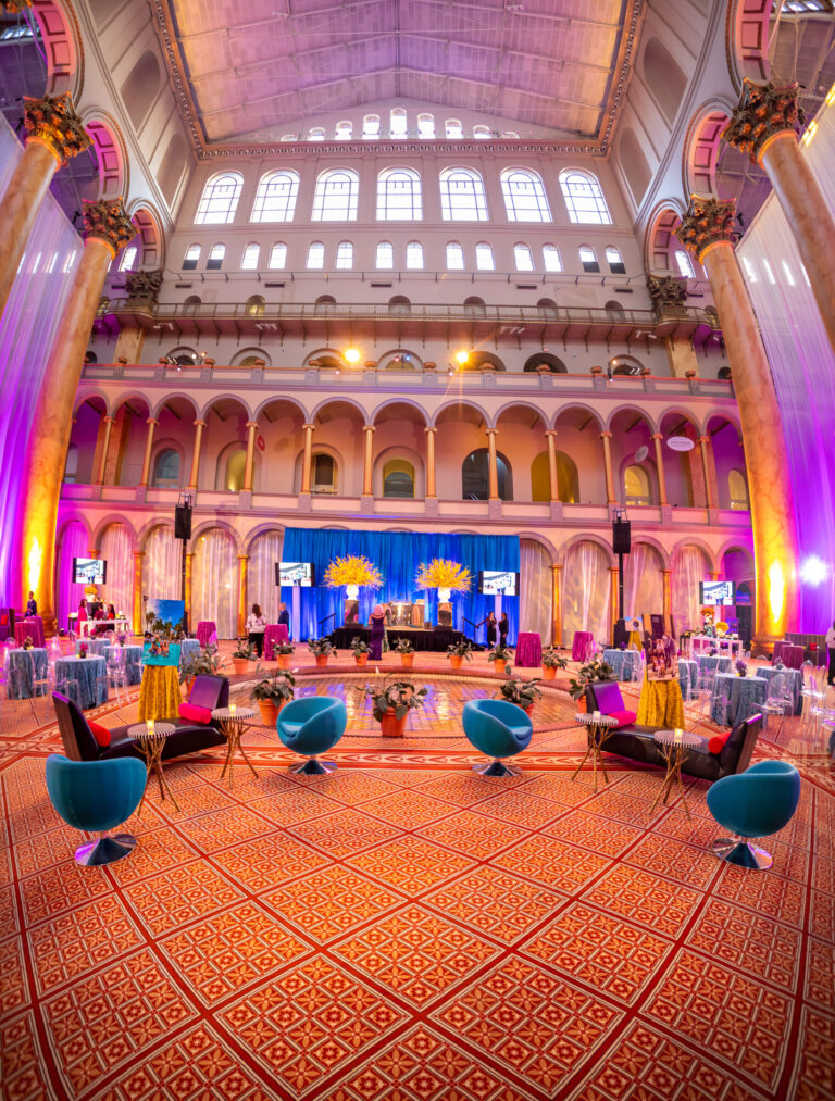 An elegant event space is decorated with colorful lounge furniture.