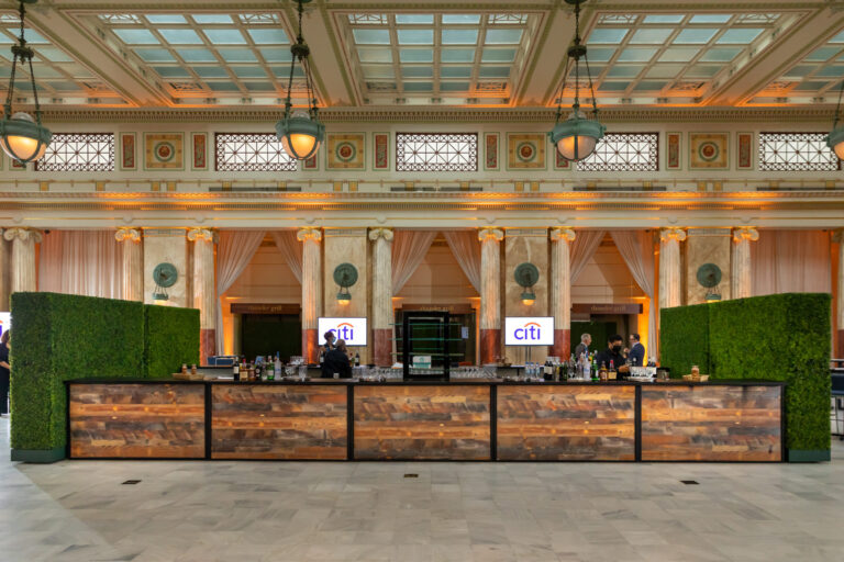 A wood bar is set up in an elegant hall. The CITI logo shows on two screens.